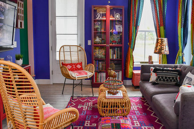 Foto de salón para visitas abierto ecléctico grande con paredes púrpuras, suelo de baldosas de porcelana, televisor colgado en la pared y suelo gris