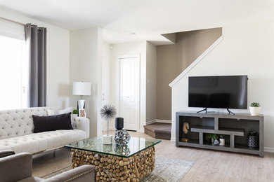 Идея дизайна: открытая гостиная комната в морском стиле с желтыми стенами, полом из ламината, отдельно стоящим телевизором и серым полом