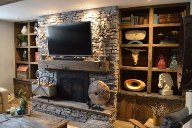 Cette photo montre un salon montagne de taille moyenne avec une bibliothèque ou un coin lecture, un mur gris, une cheminée standard, un manteau de cheminée en béton et un téléviseur fixé au mur.