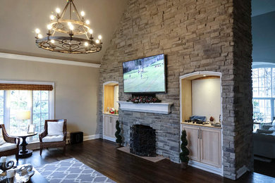 Large mediterranean open plan living room in Chicago with beige walls, dark hardwood flooring, a standard fireplace, a stone fireplace surround, a wall mounted tv and brown floors.