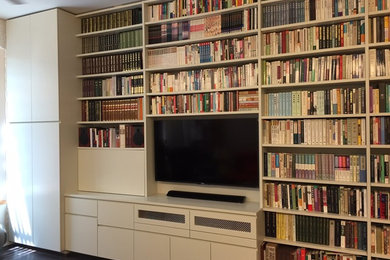 Foto de biblioteca en casa minimalista de tamaño medio con paredes blancas, suelo de madera oscura y televisor colgado en la pared