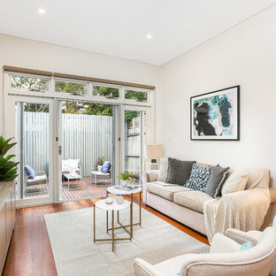 This is an example of a small beach style formal open concept living room in Sydney with medium hardwood floors, brown floor, white walls, no fireplace and no tv.