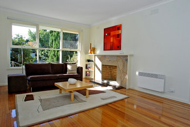 Cette photo montre un salon tendance de taille moyenne et ouvert avec un mur beige, parquet clair, une cheminée standard, un manteau de cheminée en pierre et aucun téléviseur.