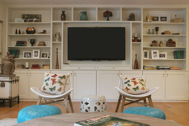 Diseño de salón abierto bohemio grande con paredes blancas, suelo de madera en tonos medios y pared multimedia