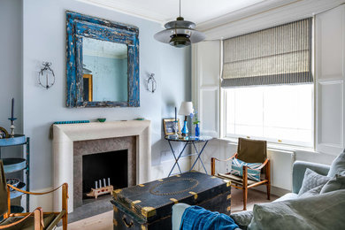 ロンドンにある小さなトラディショナルスタイルのおしゃれなリビング (青い壁、淡色無垢フローリング、標準型暖炉、テレビなし、茶色い床、青いソファ) の写真
