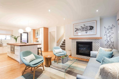 Идея дизайна: маленькая открытая гостиная комната в стиле ретро с серыми стенами, светлым паркетным полом, стандартным камином и фасадом камина из плитки без телевизора для на участке и в саду