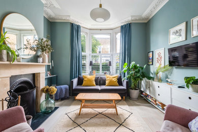 Пример оригинального дизайна: изолированная гостиная комната в стиле неоклассика (современная классика) с синими стенами, светлым паркетным полом, стандартным камином, телевизором на стене и бежевым полом