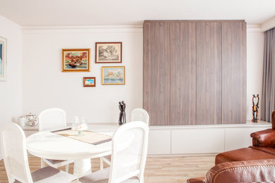Idée de décoration pour un salon design de taille moyenne avec un mur blanc, un sol en bois brun et un téléviseur fixé au mur.