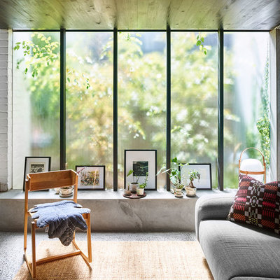 Example of a mid-sized minimalist open concept concrete floor and gray floor living room design in Brisbane with gray walls, a wood stove, a brick fireplace and a concealed tv