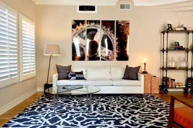 Example of a small urban open concept medium tone wood floor living room design in Los Angeles with beige walls, no fireplace and a concealed tv