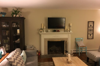 ウィルミントンにある低価格の中くらいなトラディショナルスタイルのおしゃれなリビング (ベージュの壁、淡色無垢フローリング、標準型暖炉、木材の暖炉まわり、壁掛け型テレビ、茶色い床) の写真