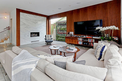 ロサンゼルスにある巨大なコンテンポラリースタイルのおしゃれなLDK (白い壁、コンクリートの床、標準型暖炉、石材の暖炉まわり、壁掛け型テレビ) の写真