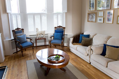 Imagen de salón abierto tradicional grande con paredes beige y suelo de madera en tonos medios