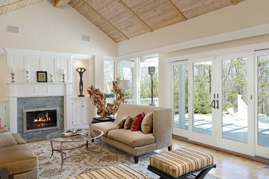Idée de décoration pour un salon tradition avec un mur beige, un sol en bois brun, une cheminée standard et un manteau de cheminée en pierre.