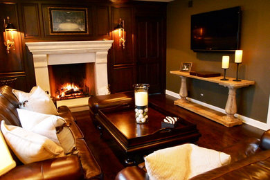 Example of a mid-sized medium tone wood floor living room design in Chicago with brown walls, a standard fireplace and a plaster fireplace