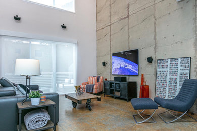 Diseño de salón tipo loft industrial grande con suelo de cemento y televisor colgado en la pared