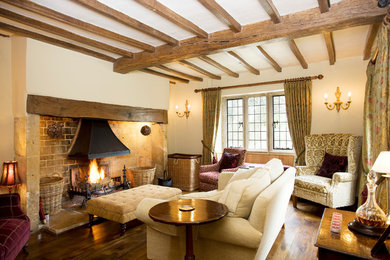 Imagen de salón de estilo de casa de campo con paredes beige, suelo de madera en tonos medios, todas las chimeneas, marco de chimenea de ladrillo y suelo marrón