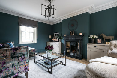 Inspiration for a medium sized classic enclosed living room in London with green walls, medium hardwood flooring, a standard fireplace, a metal fireplace surround and no tv.