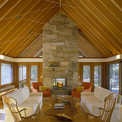 Mid-sized trendy enclosed medium tone wood floor and brown floor living room photo in Boston with a stone fireplace, beige walls and a two-sided fireplace