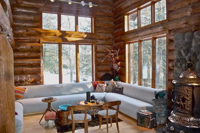Example of a mid-sized mountain style open concept living room design in New York with brown walls, a wood stove and a stone fireplace