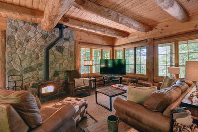 Foto de salón rural grande con paredes beige, estufa de leña, marco de chimenea de baldosas y/o azulejos, televisor independiente y suelo marrón