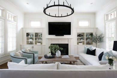 Стильный дизайн: открытая гостиная комната среднего размера в стиле неоклассика (современная классика) с белыми стенами, темным паркетным полом, стандартным камином, телевизором на стене и коричневым полом - последний тренд