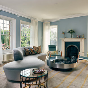 Design ideas for a contemporary living room in London with blue walls, medium hardwood flooring, a standard fireplace and brown floors.