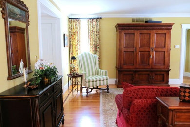 Mittelgroßes, Offenes Klassisches Wohnzimmer ohne Kamin mit gelber Wandfarbe, braunem Holzboden und verstecktem TV in New York