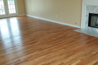 Offenes Wohnzimmer mit beiger Wandfarbe, braunem Holzboden, Kamin und Kaminumrandung aus Metall in Atlanta