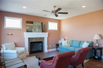 Mittelgroßes, Abgetrenntes Wohnzimmer mit oranger Wandfarbe, dunklem Holzboden, Kamin und gefliester Kaminumrandung in Grand Rapids