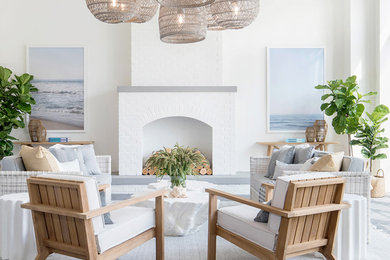 Diseño de salón para visitas abierto costero grande sin televisor con paredes blancas, todas las chimeneas, marco de chimenea de ladrillo y suelo gris