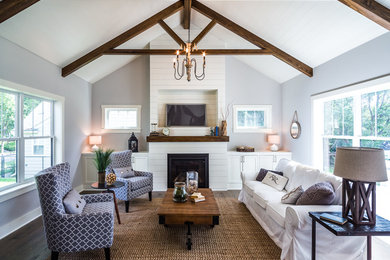 Example of a mid-sized farmhouse open concept medium tone wood floor living room design in Minneapolis with gray walls, a standard fireplace, a wood fireplace surround and a wall-mounted tv
