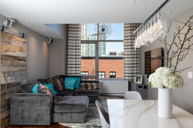 Diseño de salón abierto contemporáneo pequeño con paredes grises, suelo laminado, televisor colgado en la pared y suelo marrón