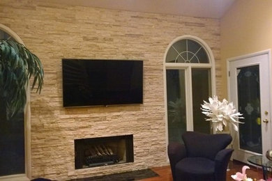 Inredning av ett klassiskt stort separat vardagsrum, med beige väggar, mellanmörkt trägolv, en standard öppen spis, en spiselkrans i sten, en väggmonterad TV och brunt golv