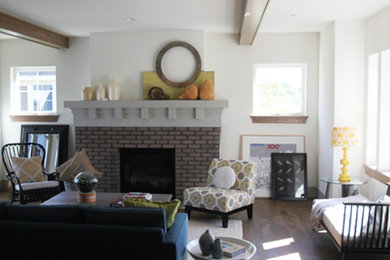 Exempel på ett mellanstort klassiskt allrum med öppen planlösning, med ett finrum, vita väggar, mörkt trägolv, en standard öppen spis, en spiselkrans i tegelsten och brunt golv