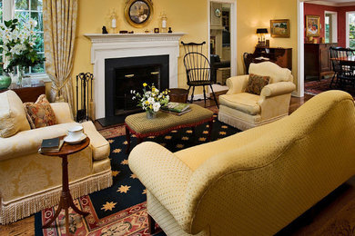 Repräsentatives Klassisches Wohnzimmer mit gelber Wandfarbe, dunklem Holzboden, Kamin und Kaminumrandung aus Stein in New York