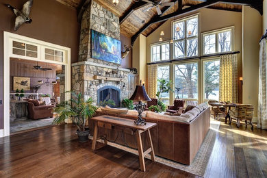 Inspiration for a huge timeless open concept and formal medium tone wood floor living room remodel in Other with a standard fireplace, a stone fireplace, brown walls and a wall-mounted tv
