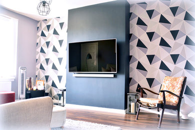 This is an example of a medium sized modern living room in Glasgow with grey walls, laminate floors, a wall mounted tv and brown floors.