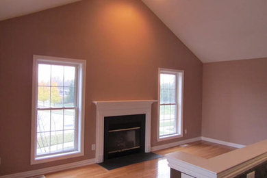 Foto de salón abierto actual grande con paredes beige, suelo de madera en tonos medios, todas las chimeneas y marco de chimenea de metal