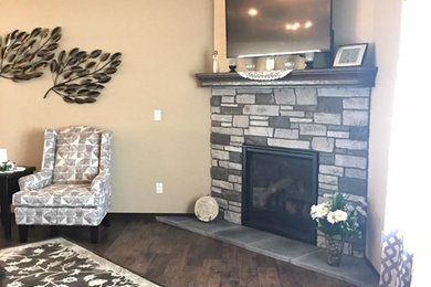 オマハにある中くらいなトラディショナルスタイルのおしゃれなLDK (ベージュの壁、無垢フローリング、コーナー設置型暖炉、石材の暖炉まわり、壁掛け型テレビ、茶色い床) の写真