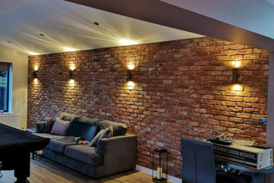 Photo of a medium sized contemporary open plan living room in Other with a reading nook, grey walls, light hardwood flooring, a wall mounted tv and brick walls.