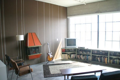 ロサンゼルスにある中くらいなコンテンポラリースタイルのおしゃれなリビングロフト (茶色い壁、コンクリートの床、吊り下げ式暖炉、据え置き型テレビ) の写真