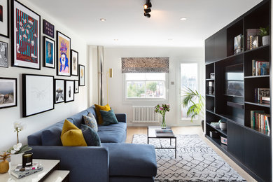 Small contemporary open plan living room feature wall in London with white walls, light hardwood flooring, a built-in media unit and no fireplace.