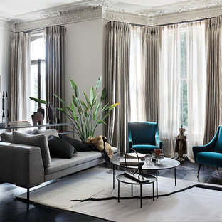 This is an example of a classic grey and teal living room in London with beige walls, dark hardwood flooring and black floors.