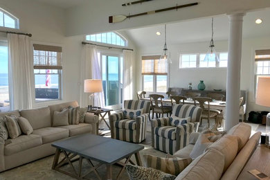 Immagine di un grande soggiorno stile marino aperto con pareti bianche, pavimento in legno massello medio, camino classico, TV a parete e pavimento marrone