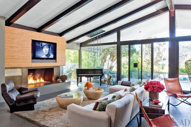 Mid-sized mid-century modern open concept concrete floor and gray floor living room photo in Los Angeles with a music area, gray walls, a standard fireplace, a concrete fireplace and a wall-mounted tv