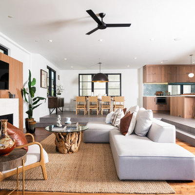 Inspiration for a contemporary open concept medium tone wood floor and brown floor living room remodel in Los Angeles with white walls, a standard fireplace, a brick fireplace and a wall-mounted tv