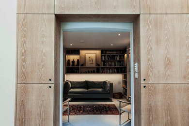 Imagen de salón cerrado moderno de tamaño medio con paredes grises, suelo de cemento, televisor colgado en la pared y suelo gris