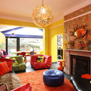 Inspiration for a medium sized bohemian open plan living room in London with yellow walls, a standard fireplace, a stone fireplace surround and black floors.