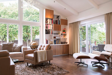 Modelo de salón abierto contemporáneo de tamaño medio sin chimenea y televisor con paredes blancas, suelo marrón y suelo de madera en tonos medios
